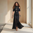 Woman wearing a black dress with a flowing skirt in a sunlit room.