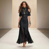 Model wearing a black dress with sheer overlay on a runway