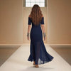 Woman in a navy blue off-shoulder dress walking on a runway.