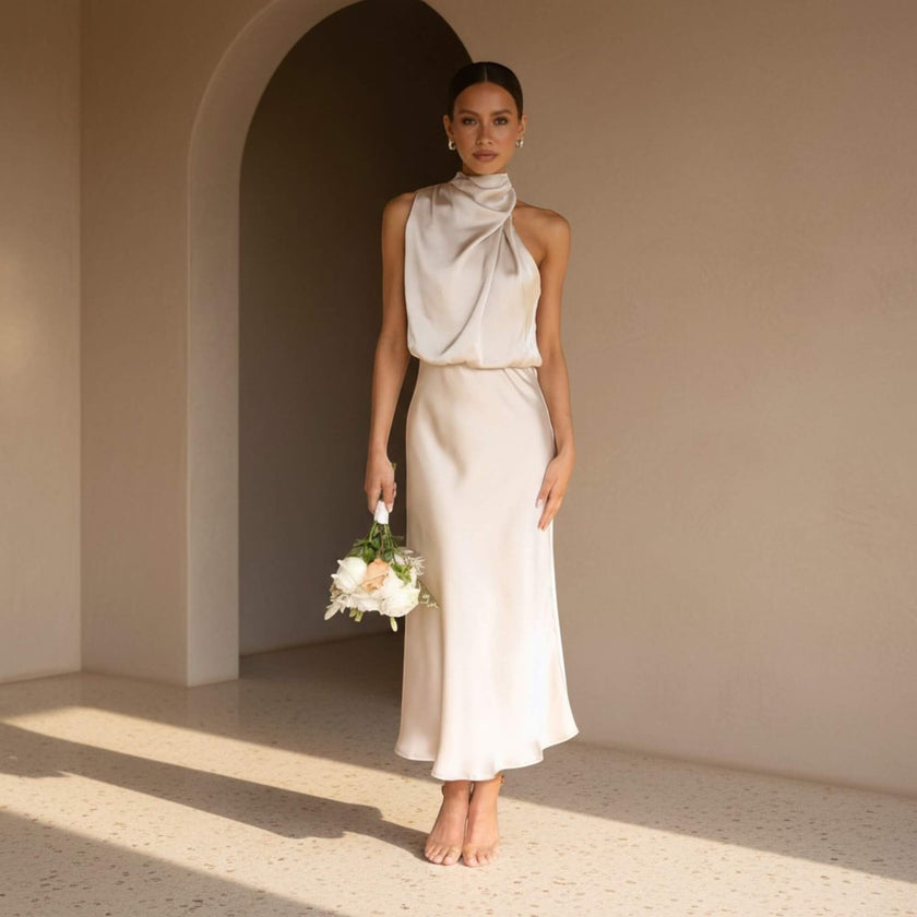 Woman in a white dress holding flowers in a sunlit room with an archway.
