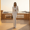 Woman in a white pinstripe suit standing on a balcony with yachts in the background