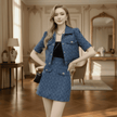 Woman in a blue textured outfit standing in an elegant room with wooden floors and decorative walls.