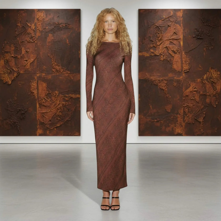 Woman in a long brown dress standing between two large textured paintings.