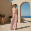 Woman in a pink outfit standing in a sunlit outdoor setting with arches and blue sky.