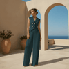Woman in a teal jumpsuit standing in front of a scenic archway with ocean view