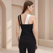 Woman wearing a black and white sleeveless top in a neutral setting
