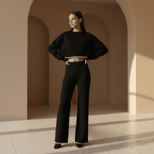 Woman wearing a black outfit standing in a sunlit archway.