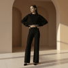 Woman wearing a black outfit standing in a sunlit archway.