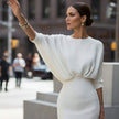Woman in a white dress waving on a city street