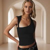 Woman wearing a black sleeveless top in an indoor setting with arches.