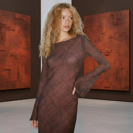 Woman in a dark red dress standing in an art gallery with abstract paintings on the wall.