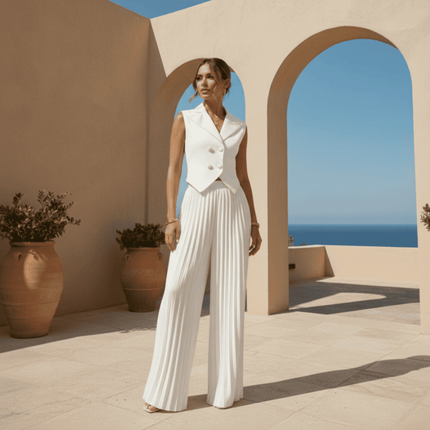 Woman in a white outfit standing on a sunlit terrace with arches and blue sky.