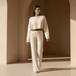 Woman in a white outfit walking through a sunlit architectural space