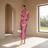 Woman in a pink dress standing in a sunlit room with arched doorways.
