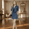 Woman in a blue outfit standing in an elegant room with wooden floors and decorative walls.