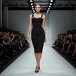 Model walking on a fashion show runway wearing a black NORVANE Riviera Bandage Dress.