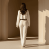 Woman in a white outfit standing in a sunlit archway