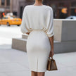 Person wearing a white dress with balloon sleeves on a city street.