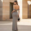 Woman in a gray dress standing in front of a beige building