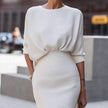 Person wearing a white ribbed dress with a blurred background