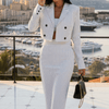 Woman wearing a white and black striped suit with sunglasses and a red handbag on a white background
