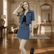 Woman in a blue outfit standing in an elegant room with wooden floors and decorative furniture.