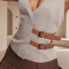 Person wearing a gray ribbed top with brown belt and pants in a neutral setting