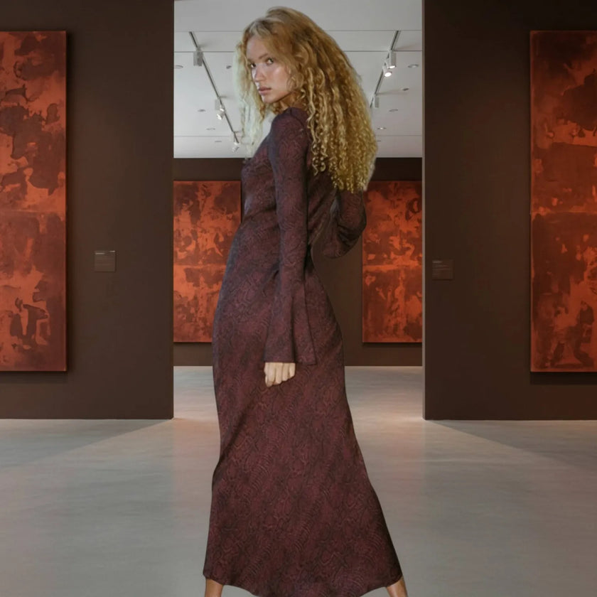 Woman in a long, dark red dress standing in an art gallery with abstract paintings on the walls.
