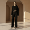 Woman wearing a black outfit standing in a sunlit archway.
