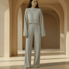 Woman wearing a light gray outfit standing in an architectural setting with arches.