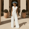 Woman in a white outfit standing on a sunlit terrace.
