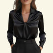 Black satin blouse with a knot detail on a beige background