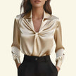 Beige satin blouse with a knot detail worn by a person on a beige background