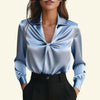 Blue satin blouse with a knot detail on a beige background