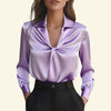 Purple satin blouse with a knot detail worn by a model on a beige background