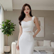 Woman in a white dress standing in a modern living room.