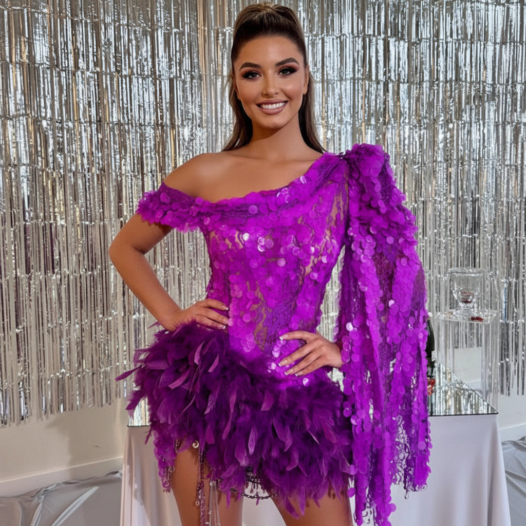 Woman wearing a purple sequin and feather dress against a silver curtain background